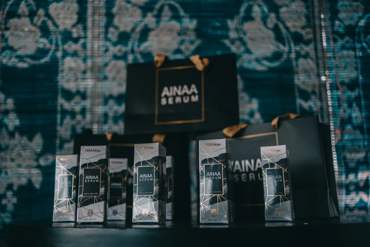Ainaa Serum bottles and boxes on a patterned backdrop.