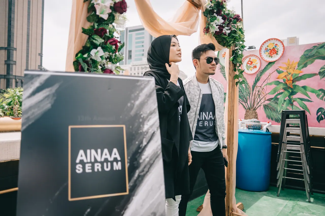 Guests beside an Ainaa Serum sign on the rooftop.