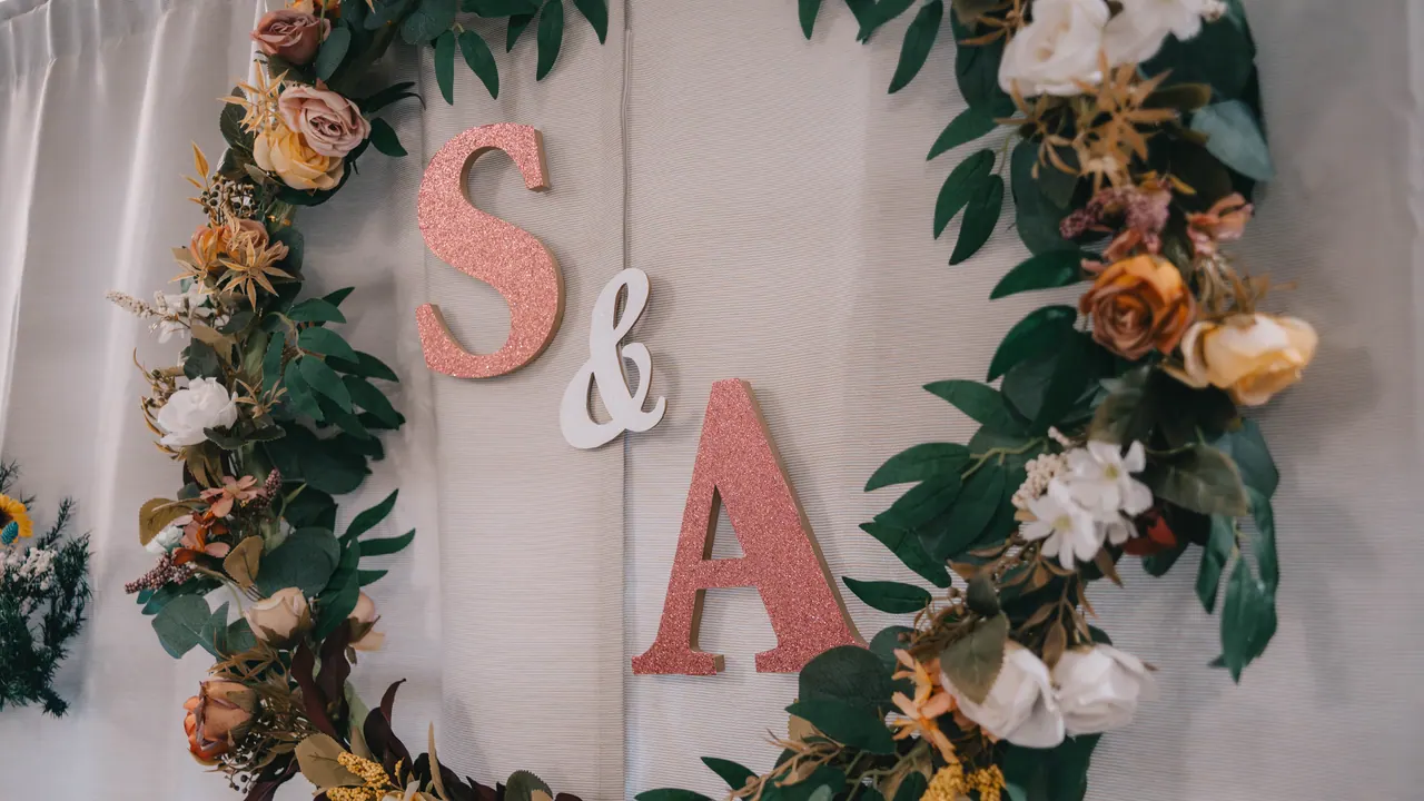 A floral wreath on a curtain, with the letters S & A.