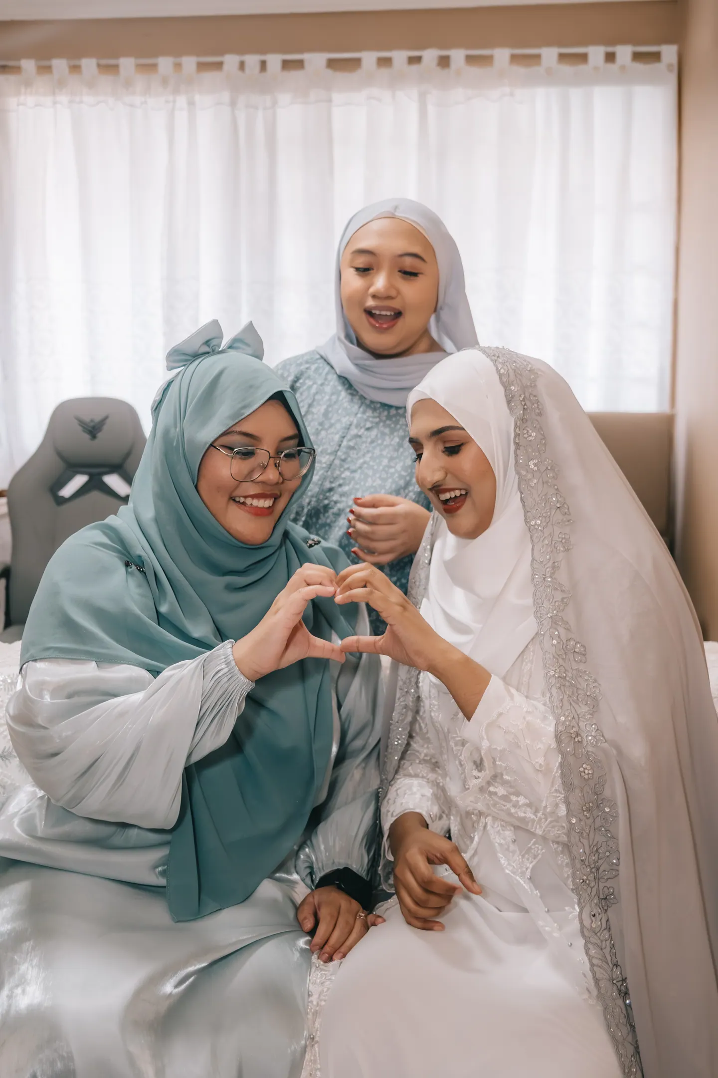 Two friends make a heart with their hands beside the bride-to-be.