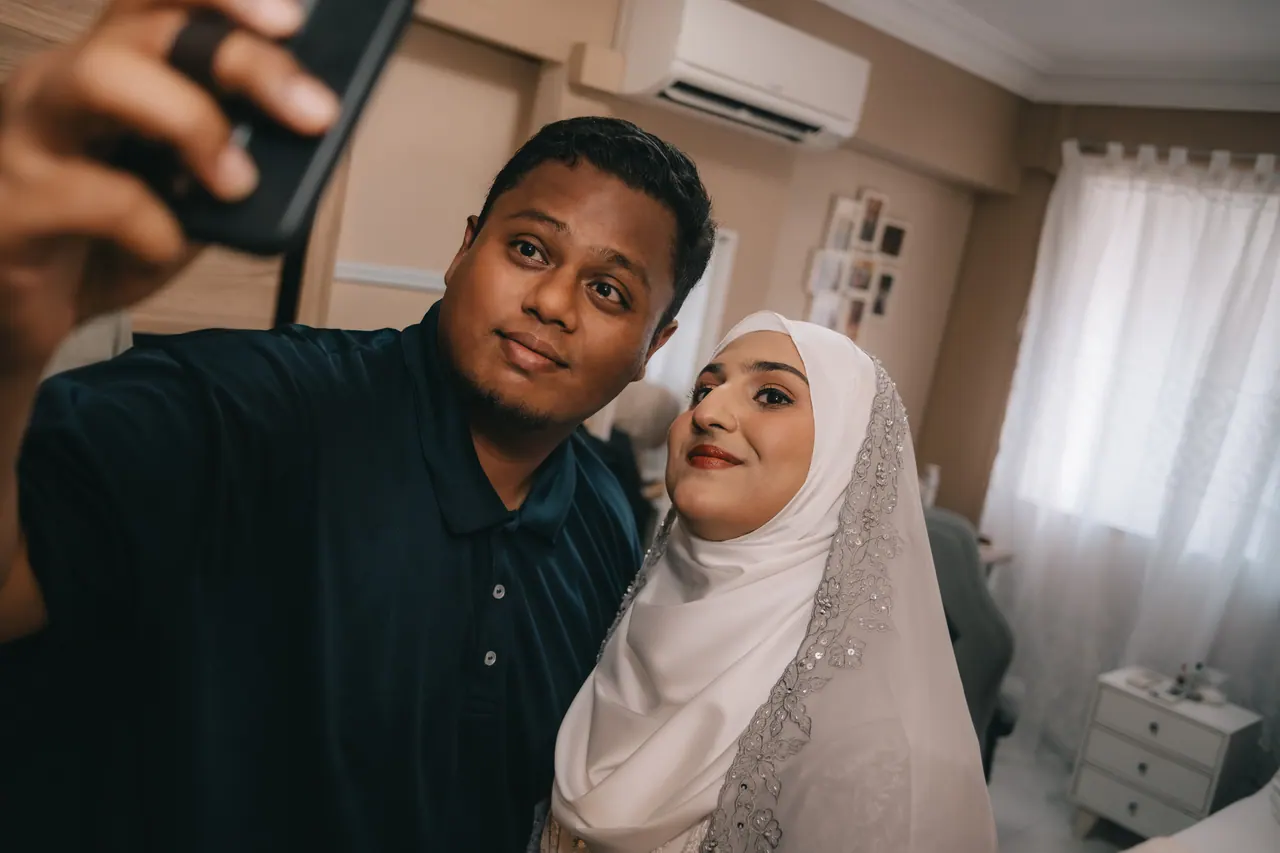 A man holds up his phone for a selfie with the bride-to-be.