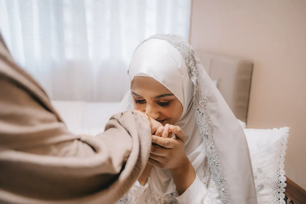 Close: she presses the woman’s hand to her lips.