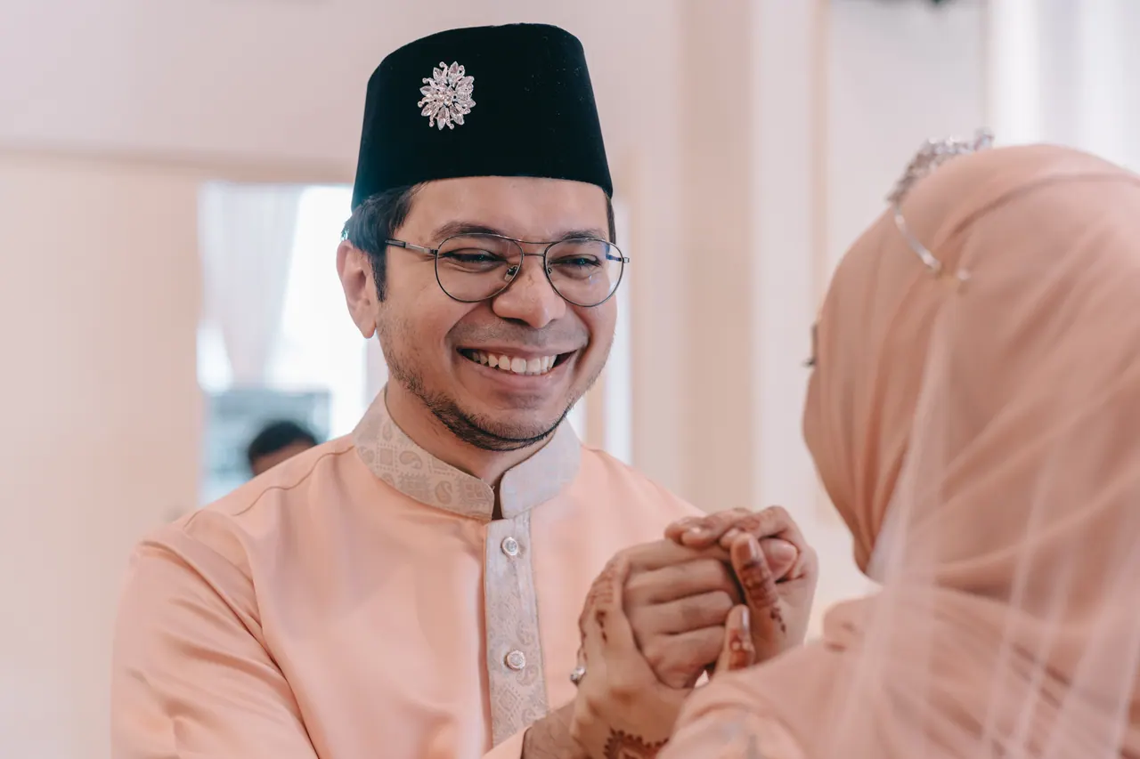 The groom laughs as he holds the bride’s hennaed hand.