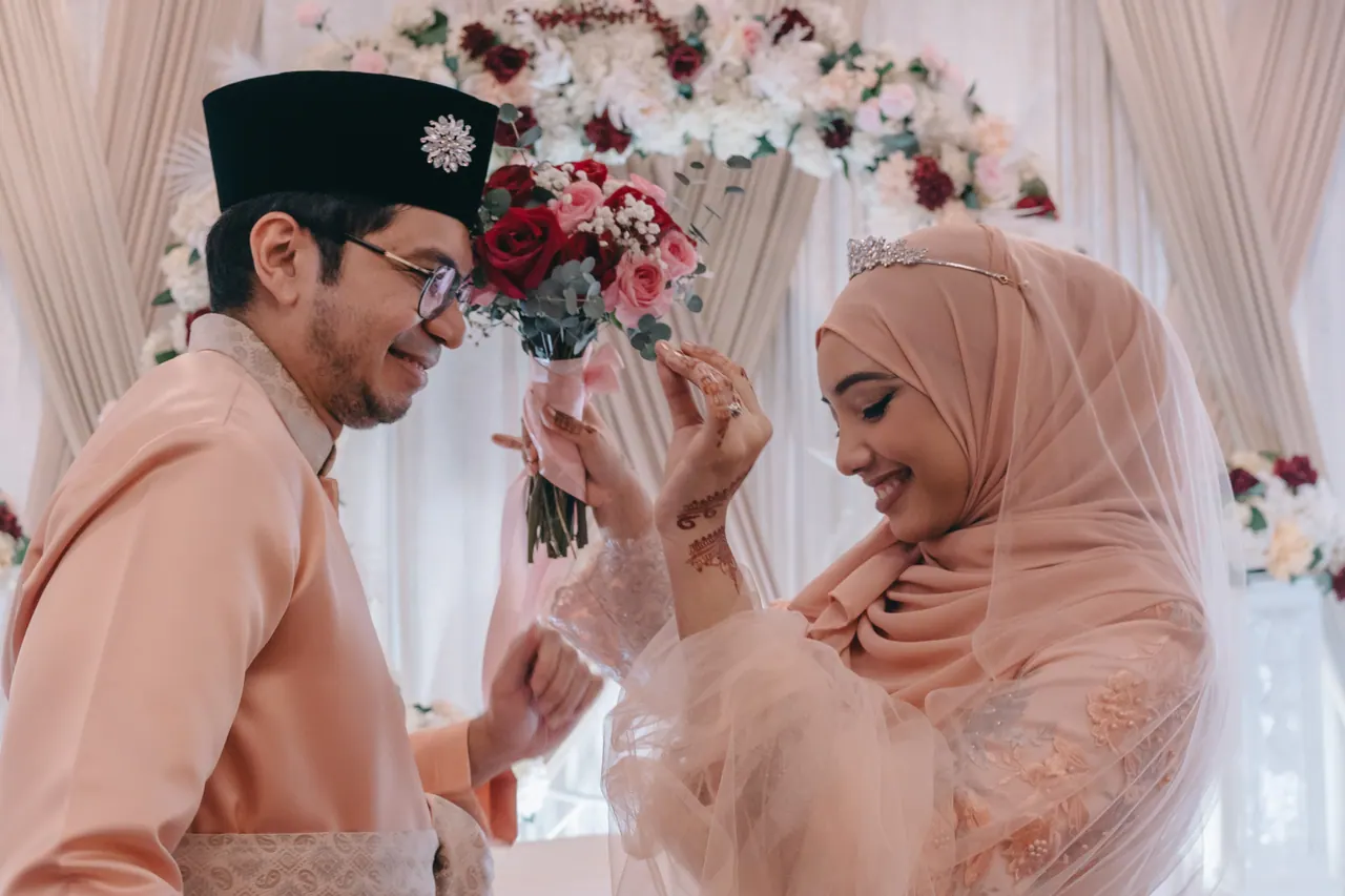The groom offers the bouquet and the bride laughs.