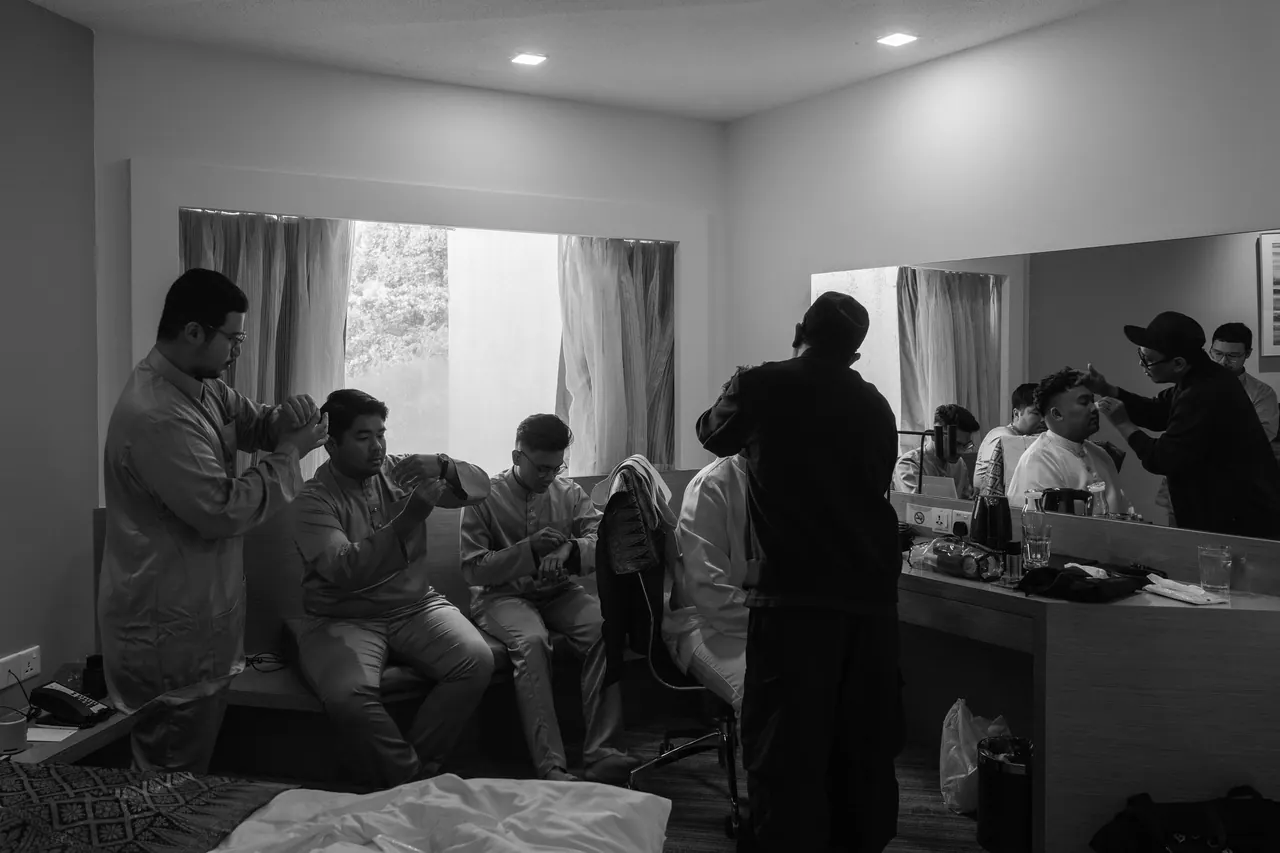 Black and white: the groom’s side gets ready in a crowded room.