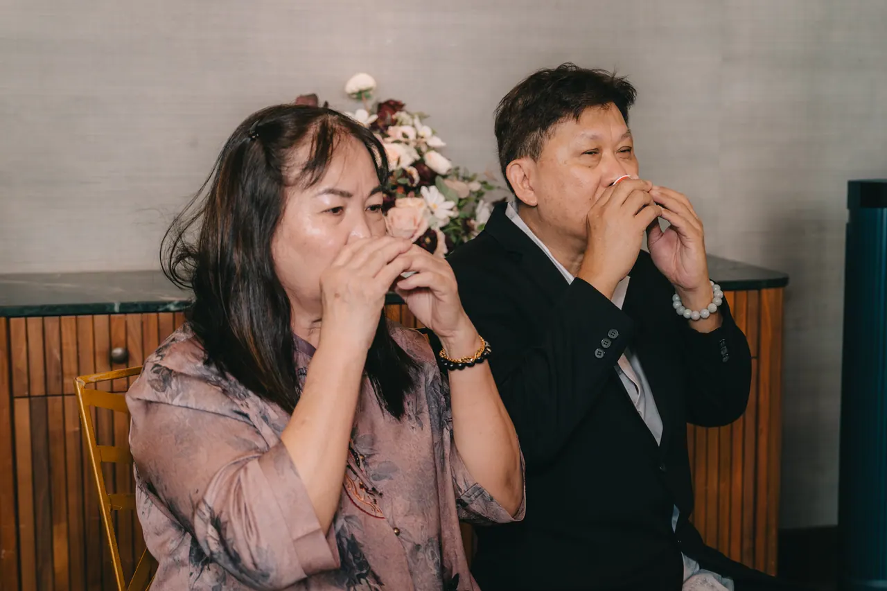 An older couple drink their tea at the same moment.