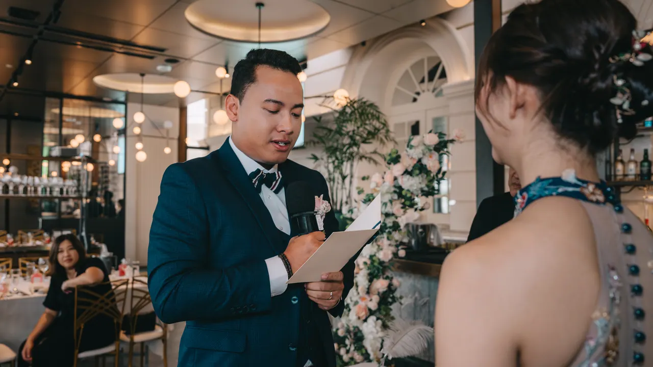 The groom reads his vows from a card.