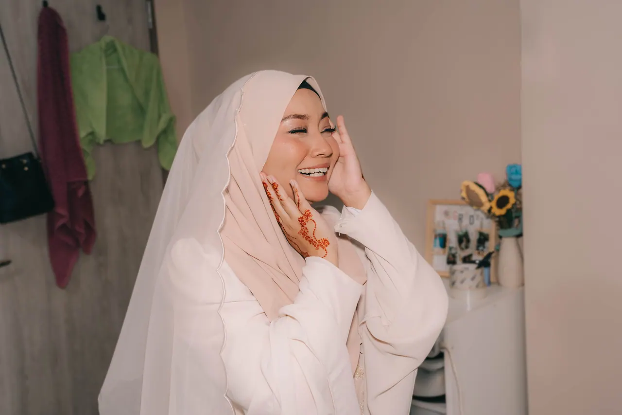 The bride-to-be laughs, one hand at her cheek.