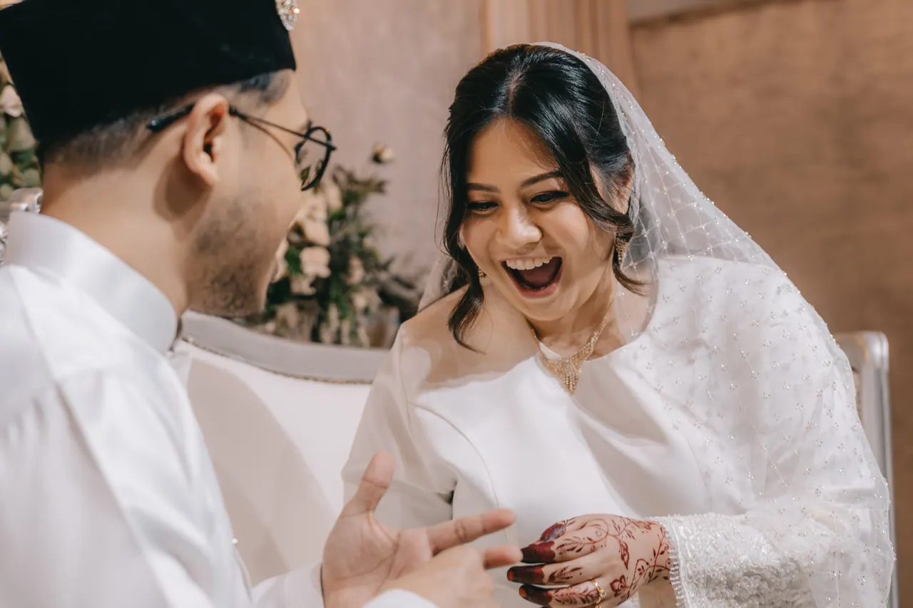 The bride gasps with delight as the groom reaches for her hand.