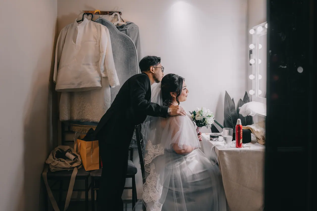 In the dressing room, the groom leans in to speak to the bride.