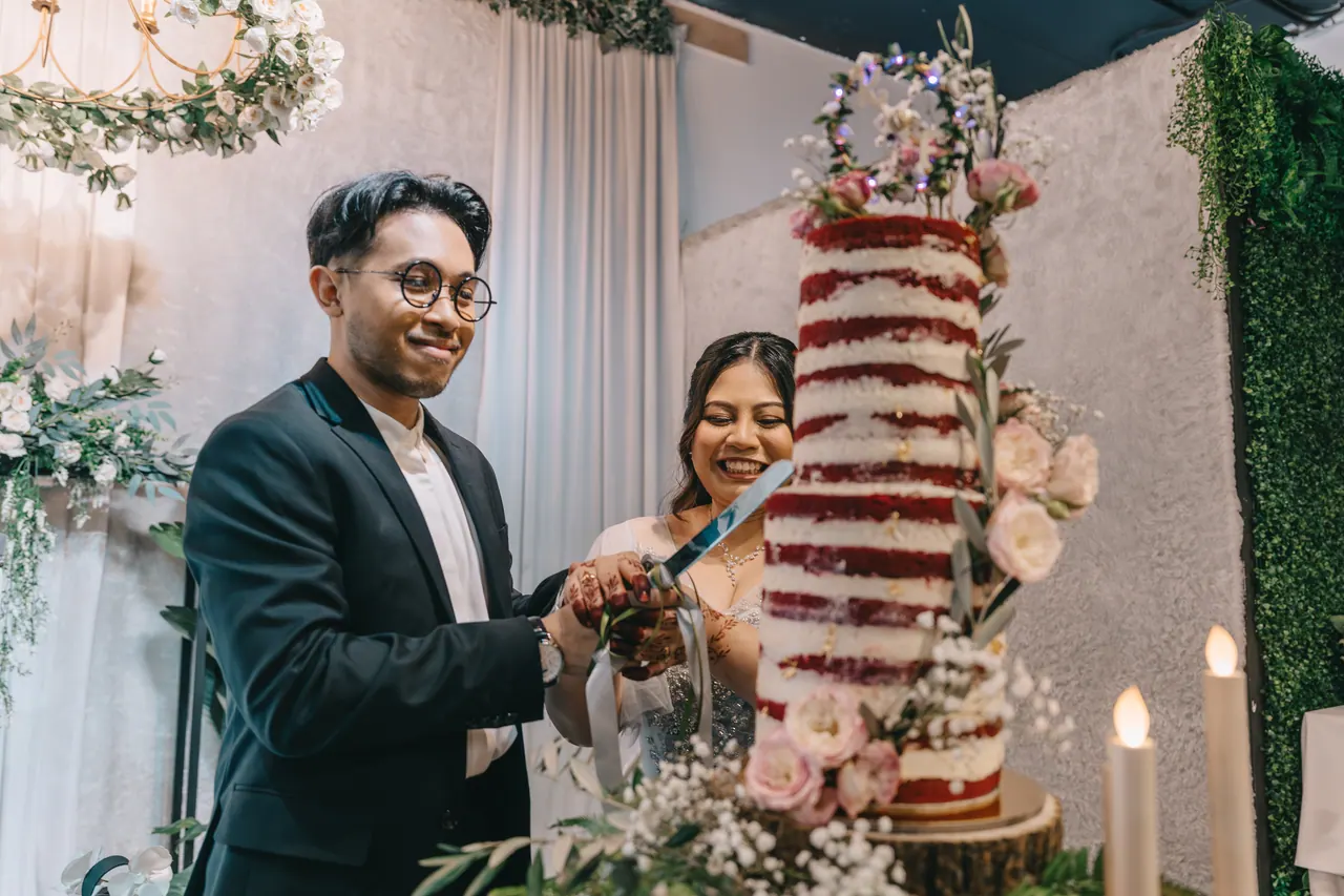 The couple cut a tall red velvet cake by candlelight.