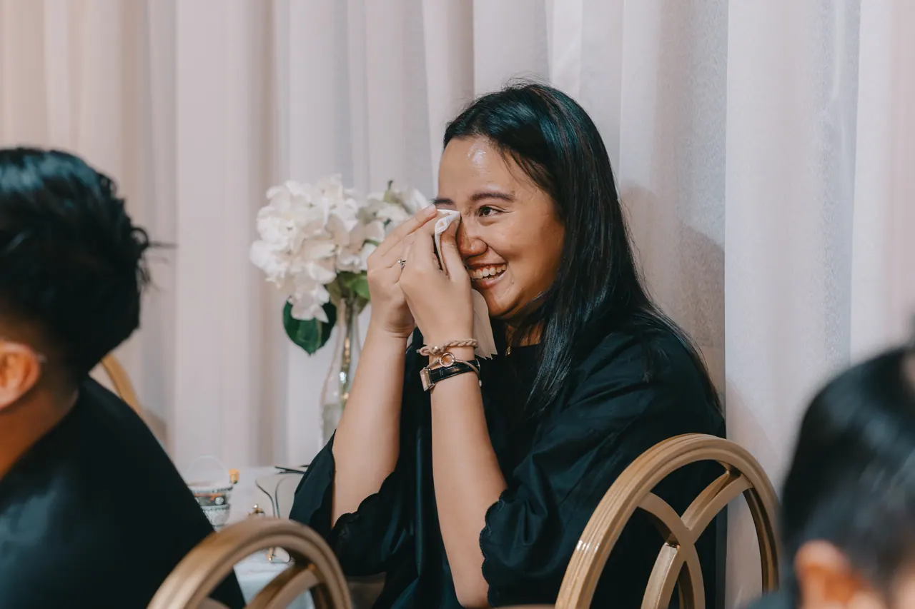 A guest laughs and wipes her eyes at the same time.