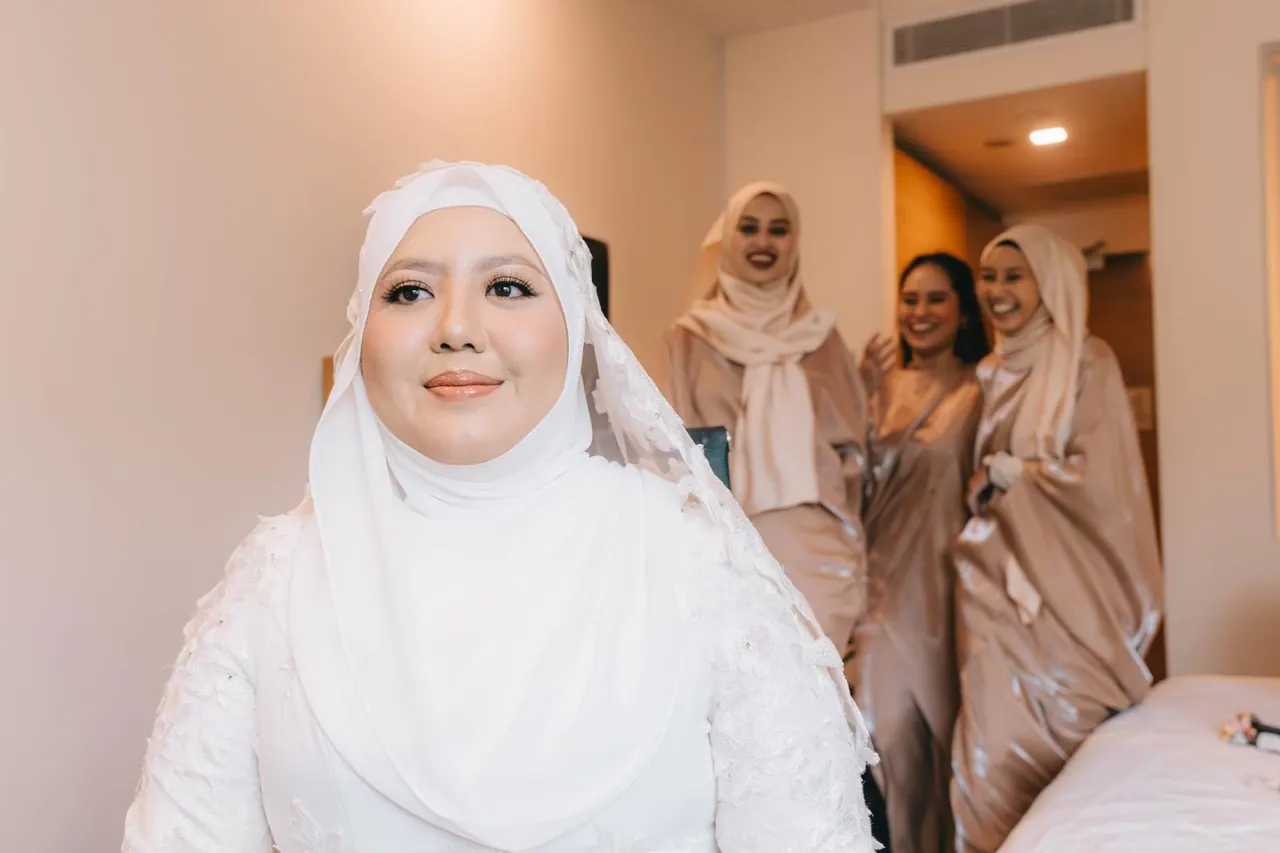 The bride in white, ready, with her bridesmaids smiling behind her.