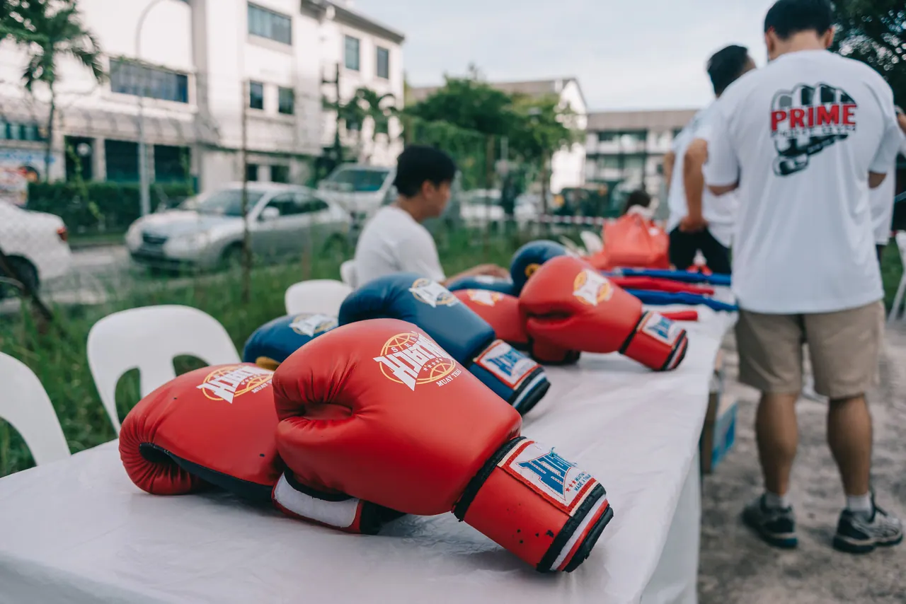 Red boxing gloves laid out on a table outdoors.