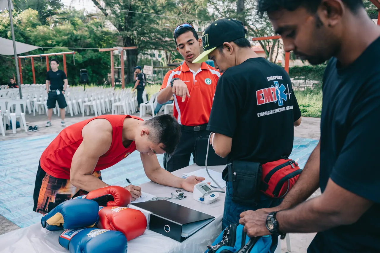 Officials check a fighter’s hand wraps at a table.