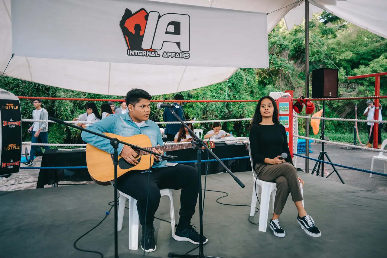 A guitarist and a singer perform under a tent.