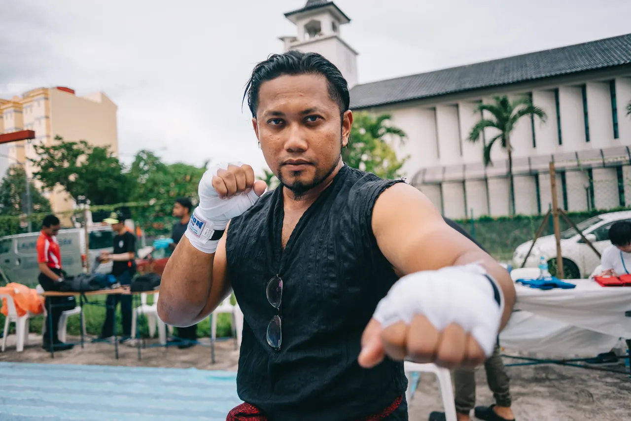 A fighter in hand wraps throws a punch at the camera.