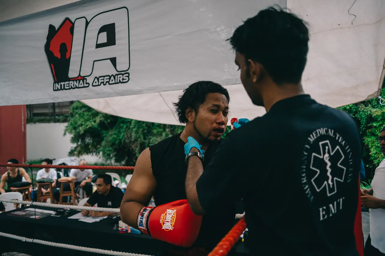 A fighter has his gloves checked by an official.