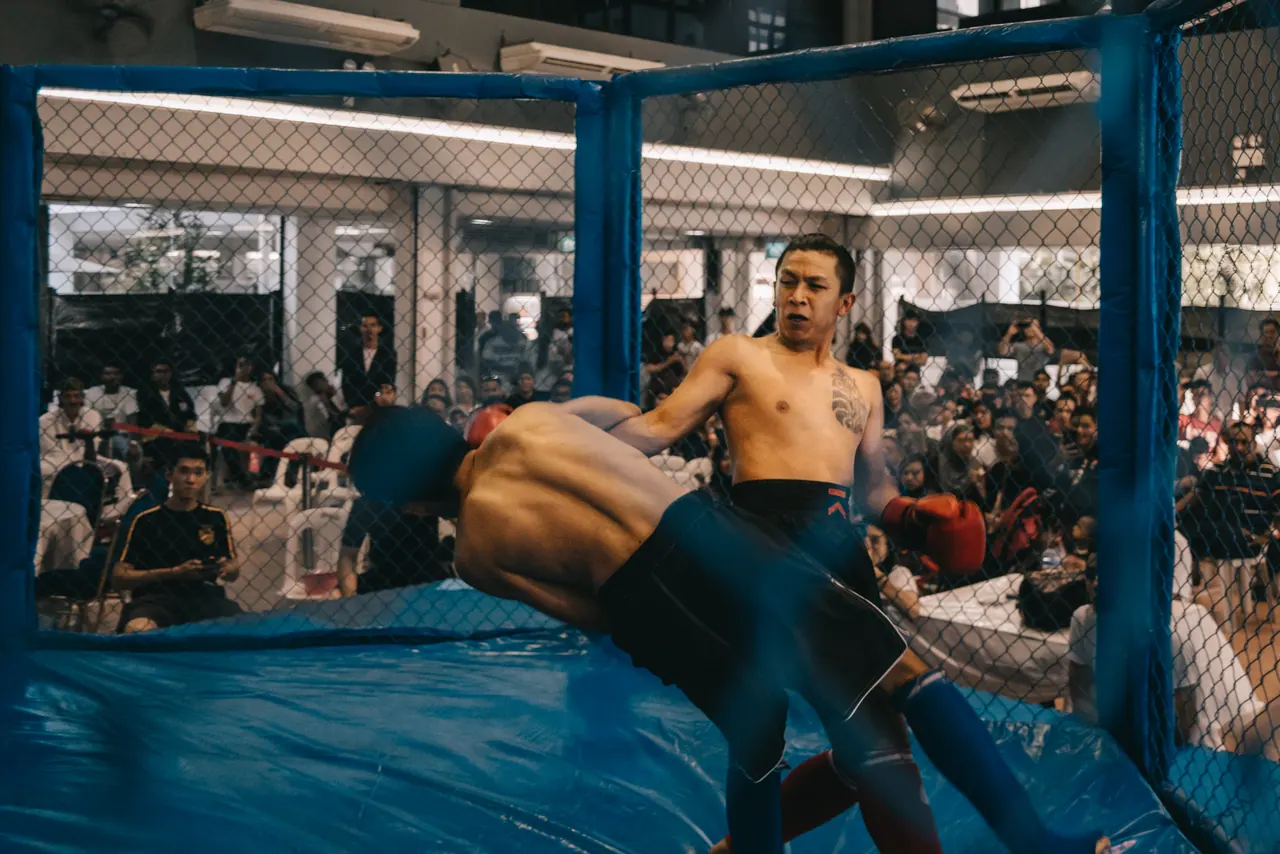 A takedown against the cage wall.
