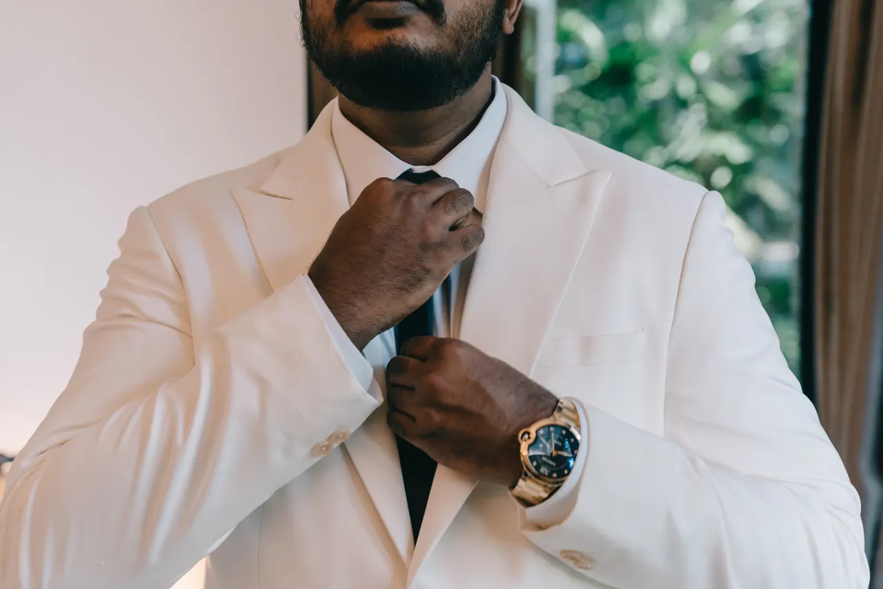 The groom straightens his tie.