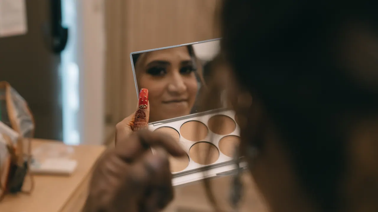 The bride checks her make-up in a small mirror.