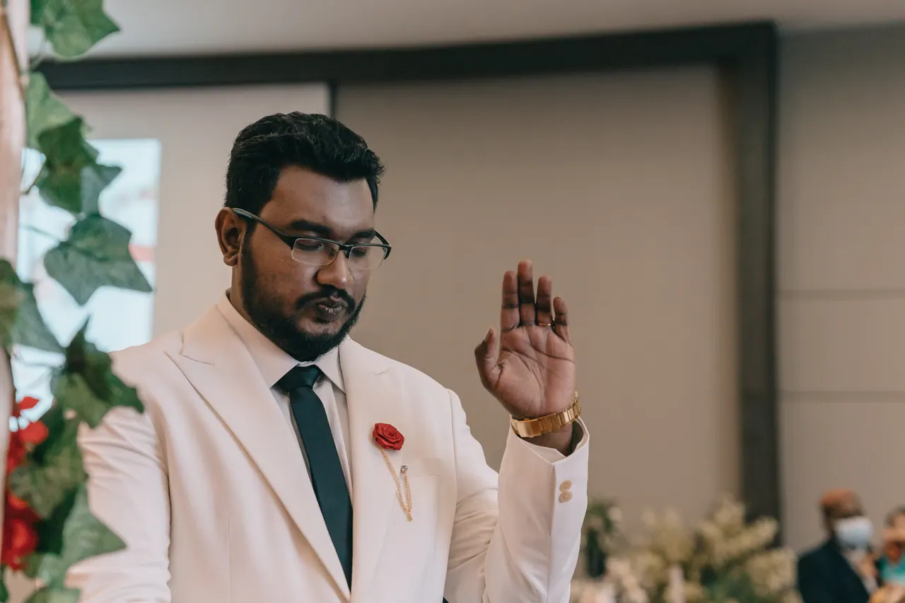 The groom raises his hand in worship.