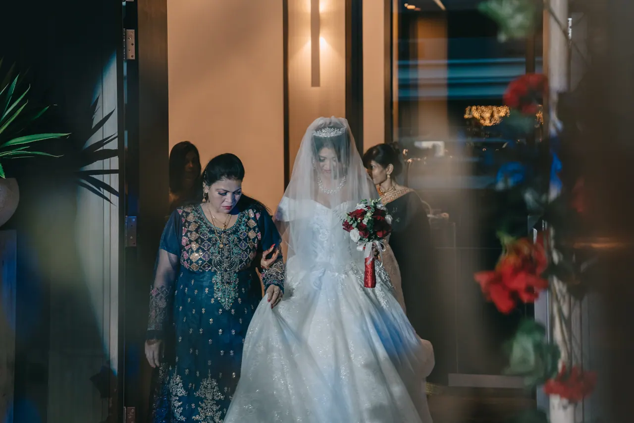 The bride walks in on a woman’s arm.