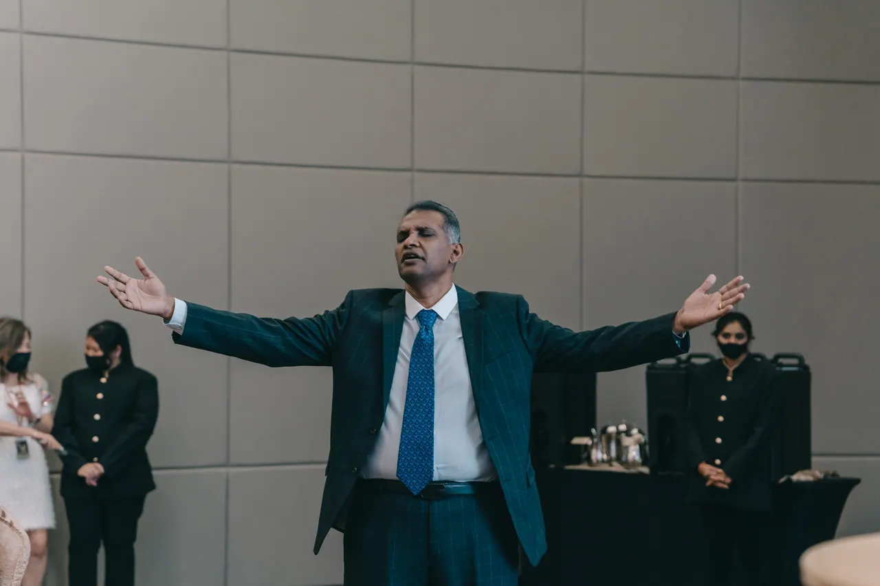 A man in a blue suit opens his arms wide.