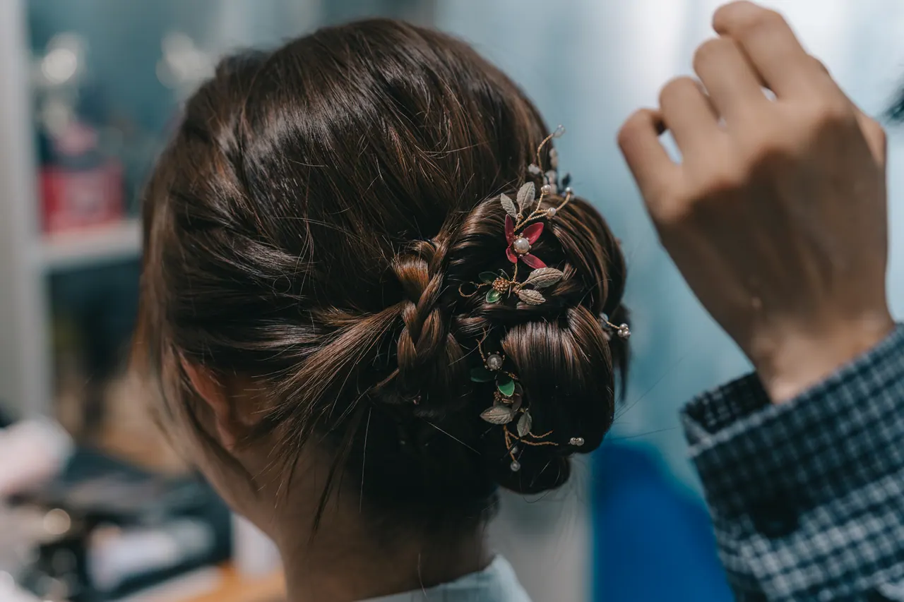 The bride’s braided bun, a hand reaching in to finish it.