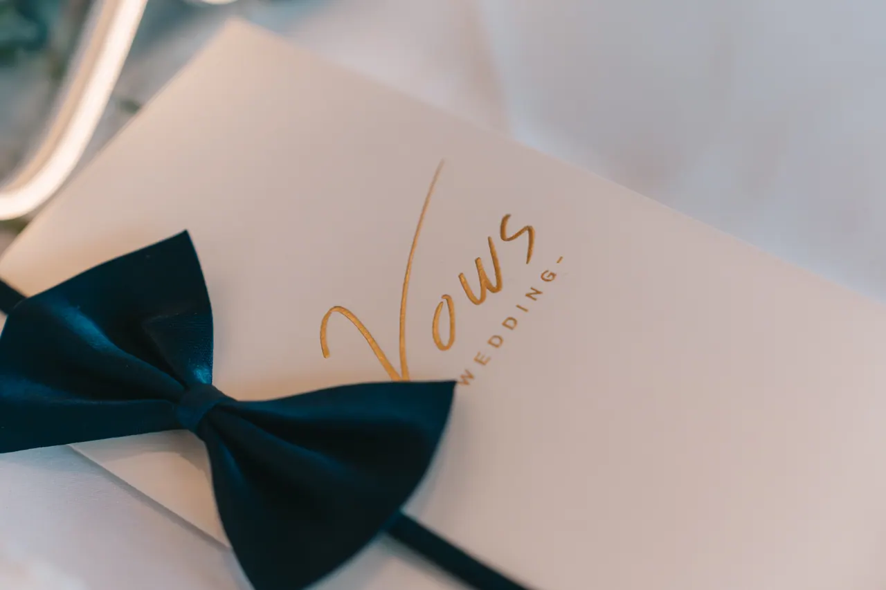 A wedding vows card tied with a navy bow.