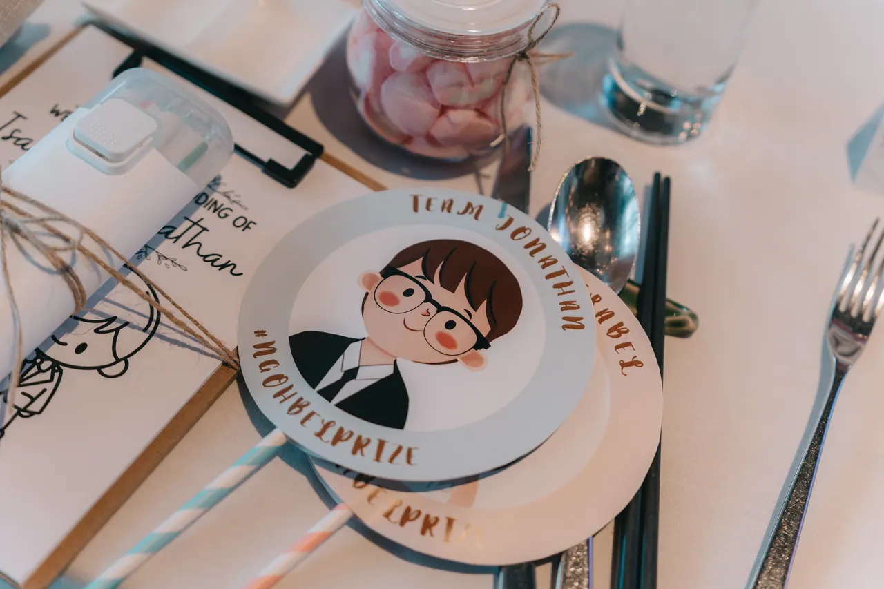 A place card with a cartoon of the groom on a set table.