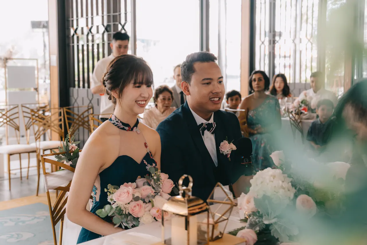 The couple seated together as guests look on.