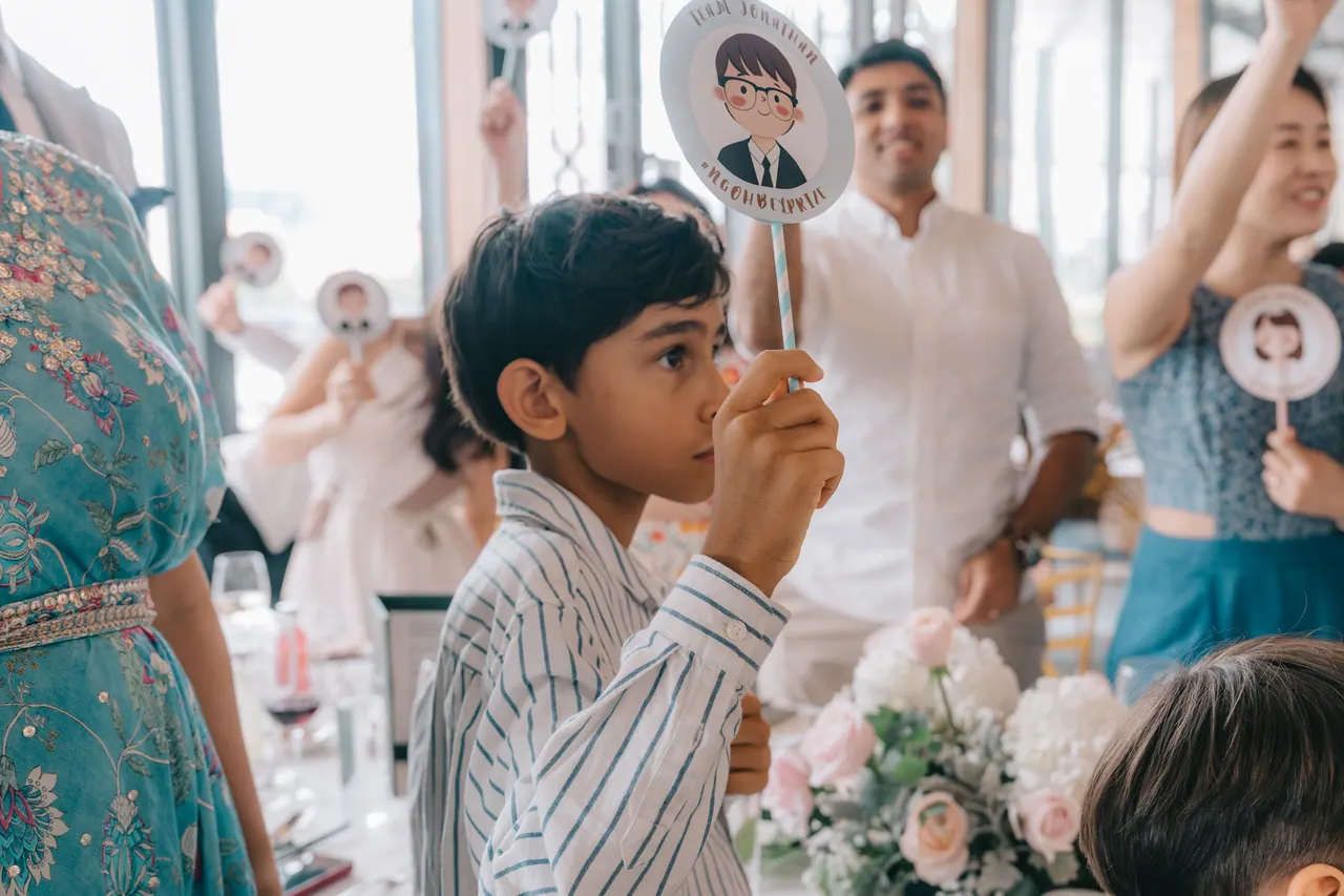 A boy holds up a cartoon face on a stick.