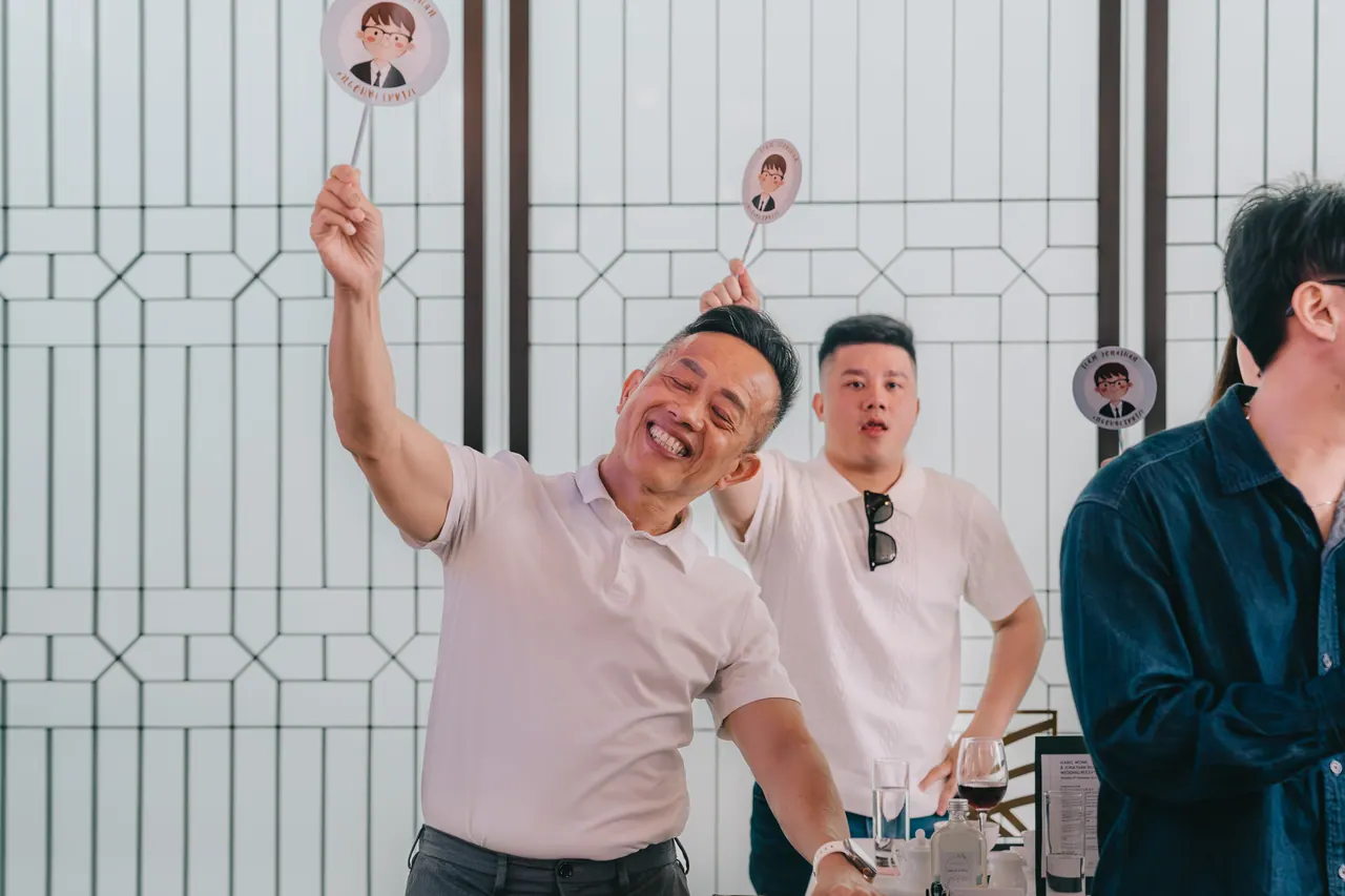 A guest throws his arm in the air, laughing.