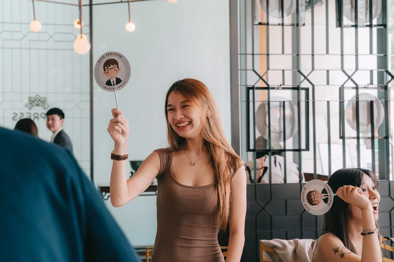A guest laughs, holding up a cartoon face of the groom.