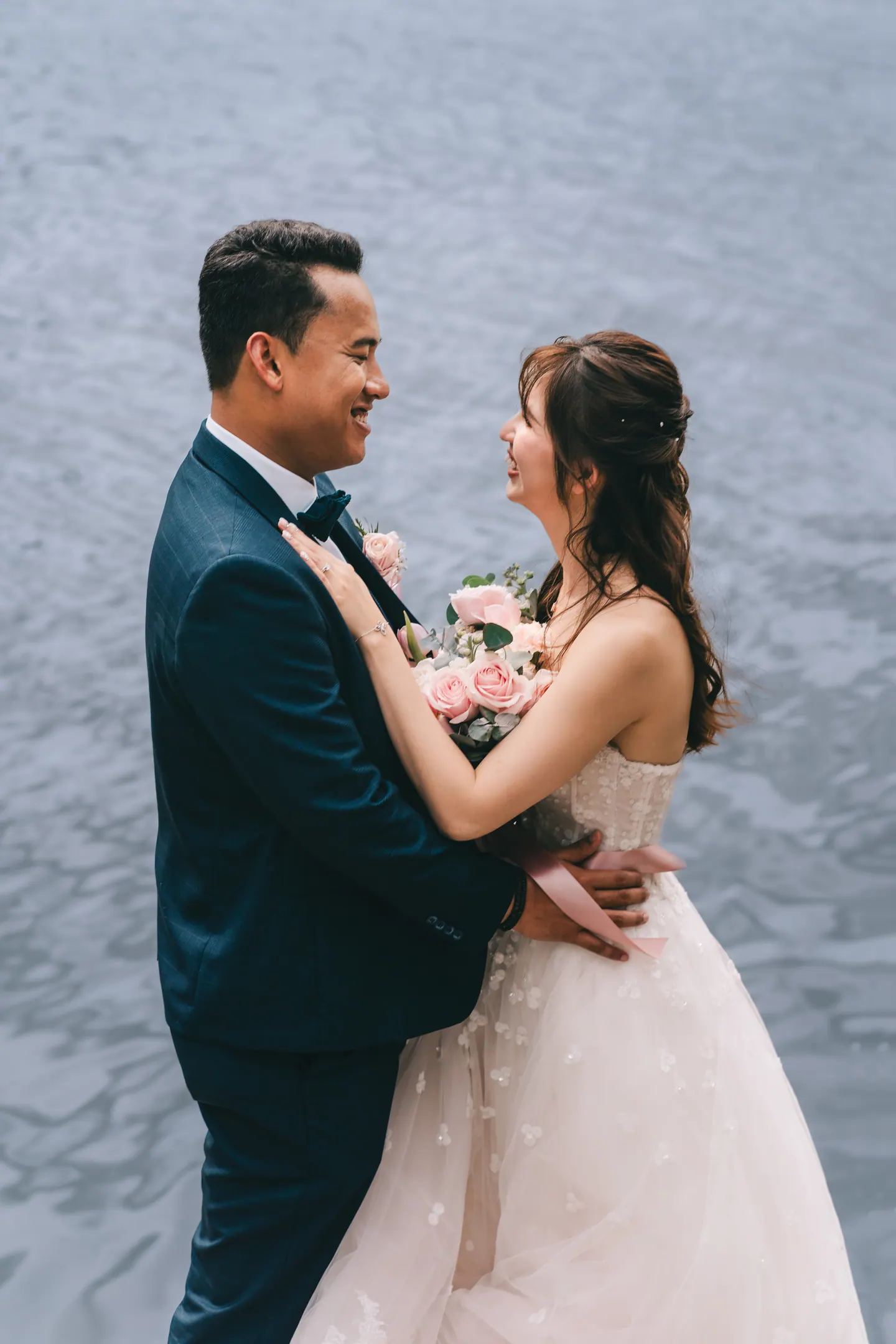 The couple embrace beside the river.