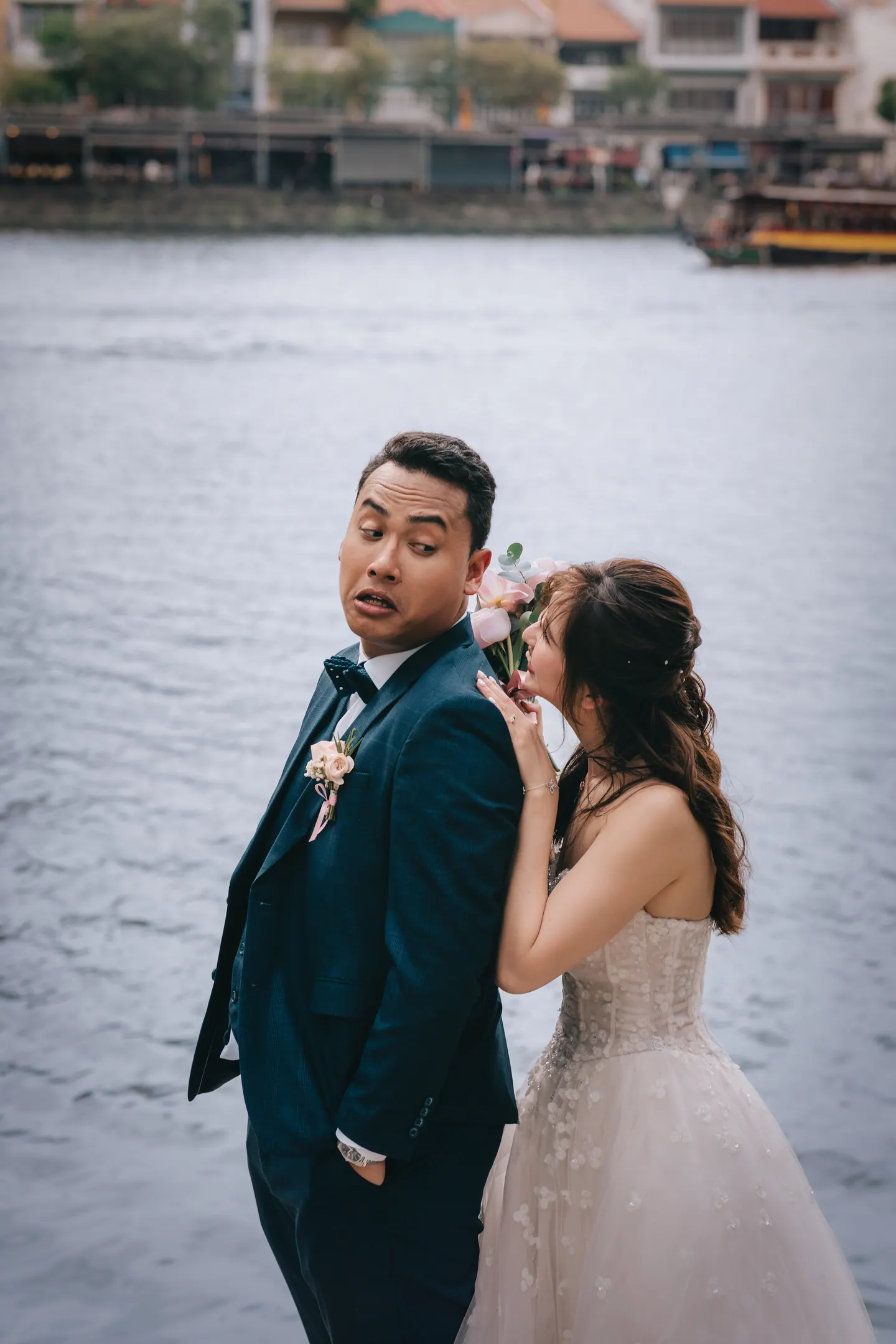 The groom kisses the bride beside the river.