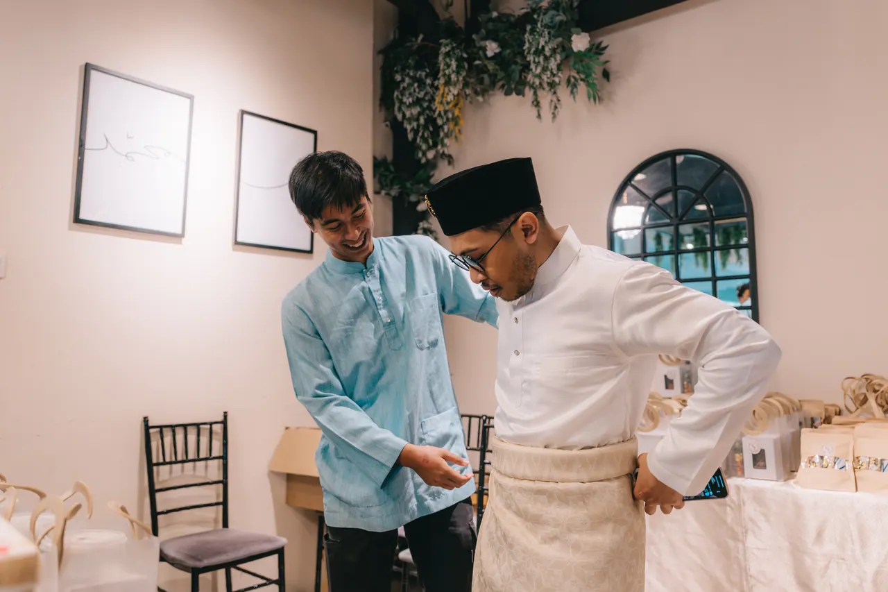 The groom’s friend straightens his sampin before the ceremony.