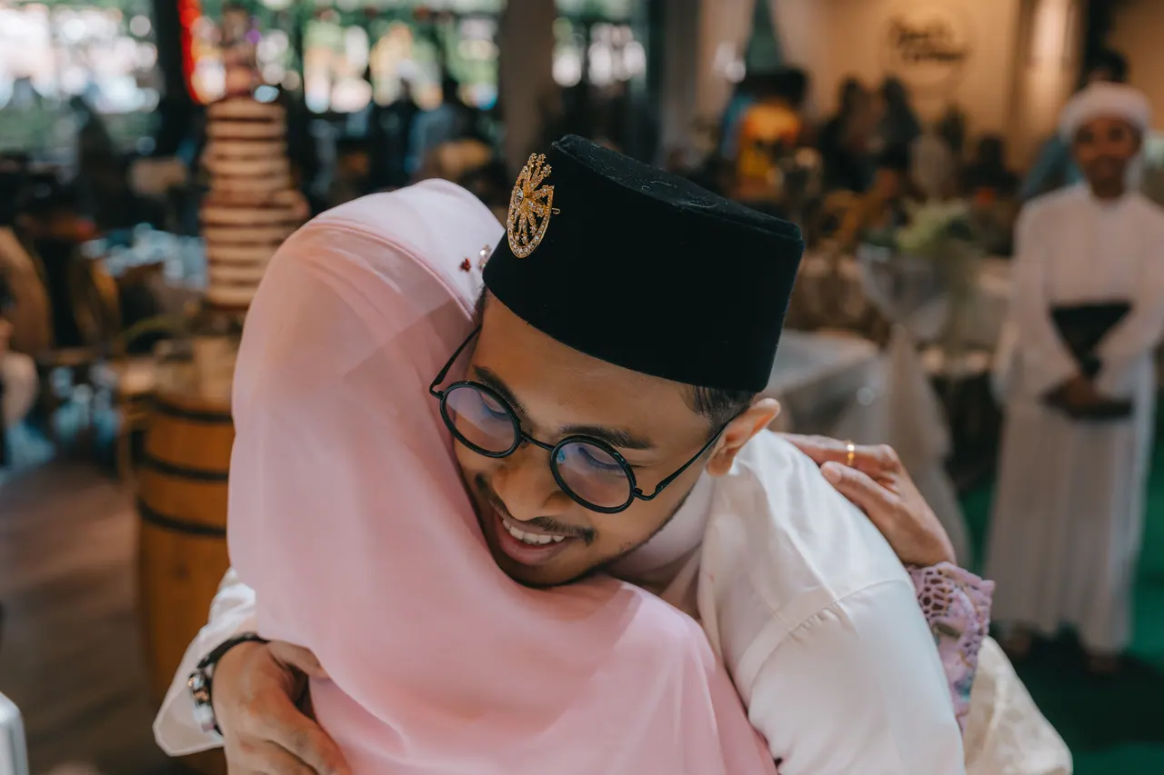 The groom hugs a woman in pink tightly.