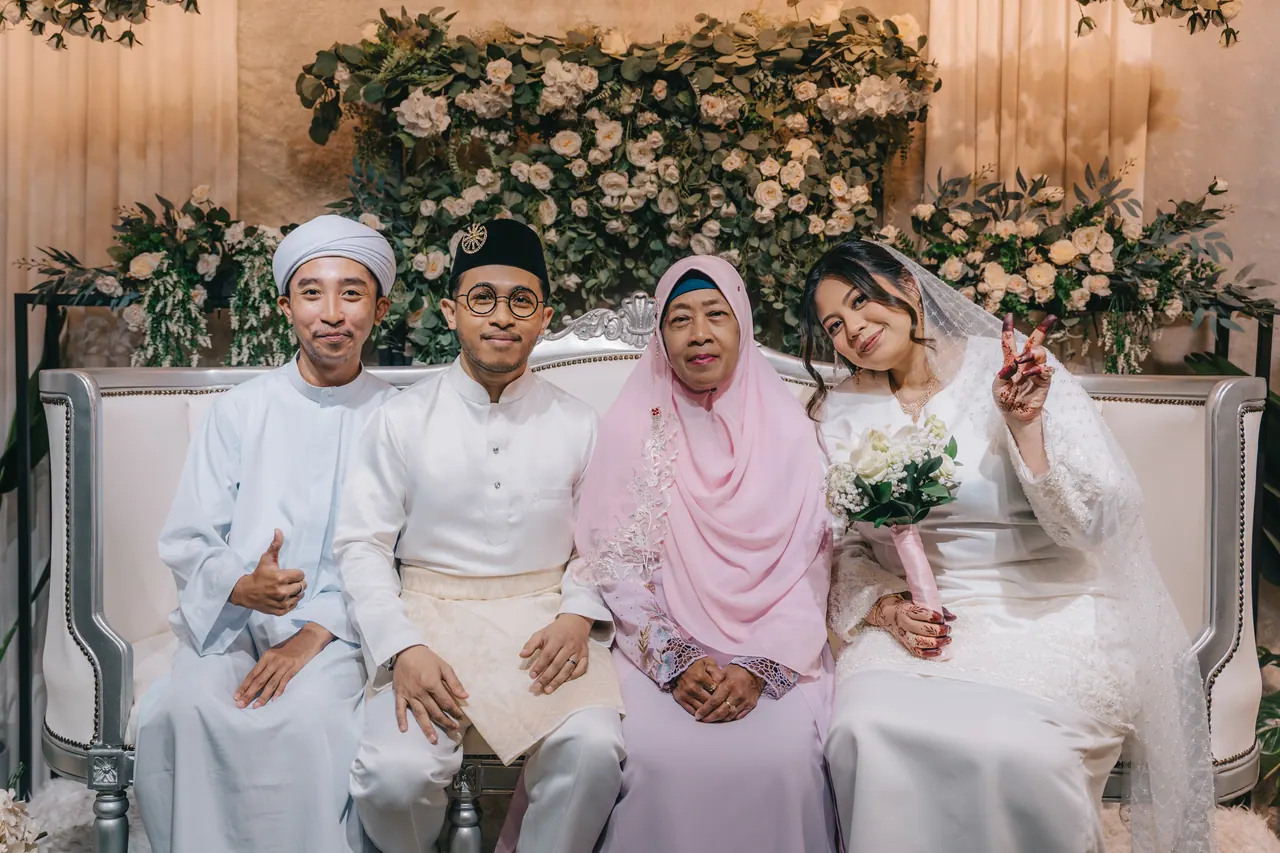 The couple seated on a floral bench with their parents.
