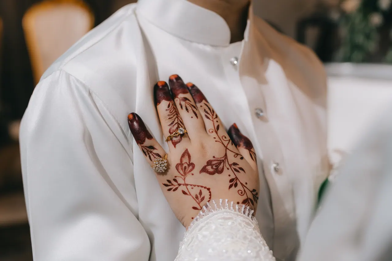 The bride’s hennaed hand rests on the groom’s chest.