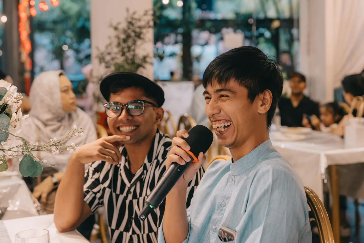 Two guests laugh into a microphone.