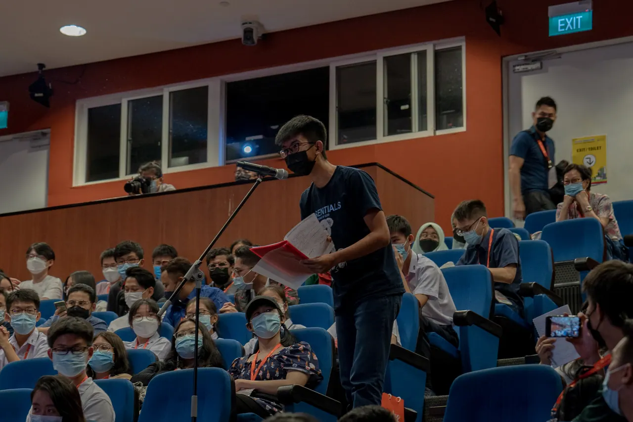 The audience listens as a camera operator films.