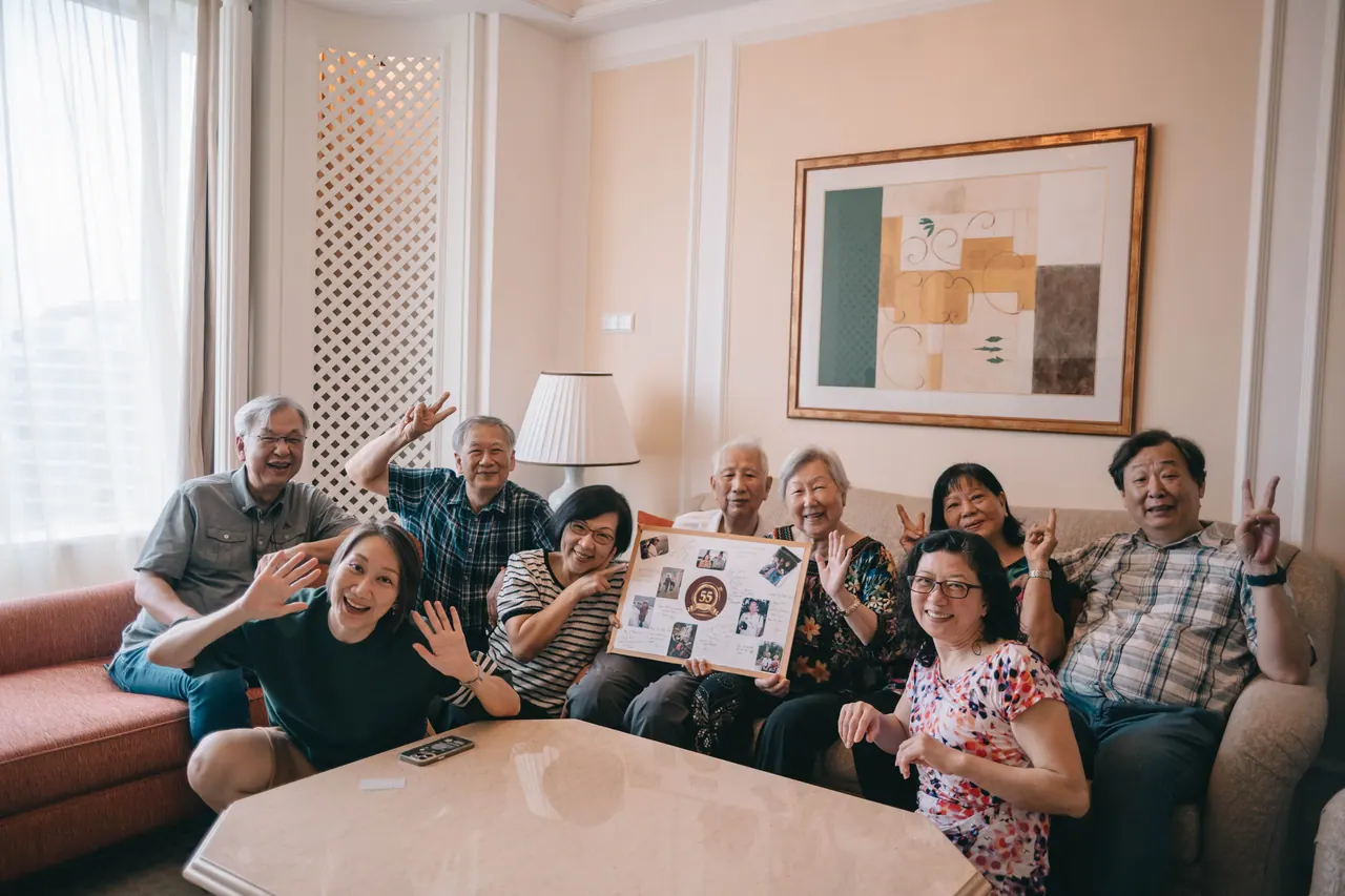 The whole family on a sofa, holding up a photo board.
