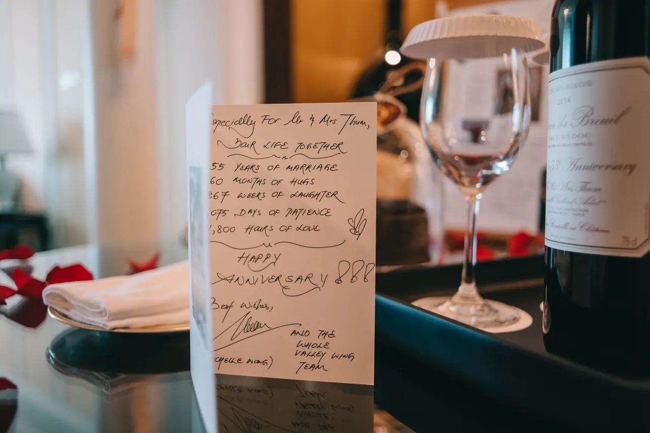 A handwritten card beside wine glasses.
