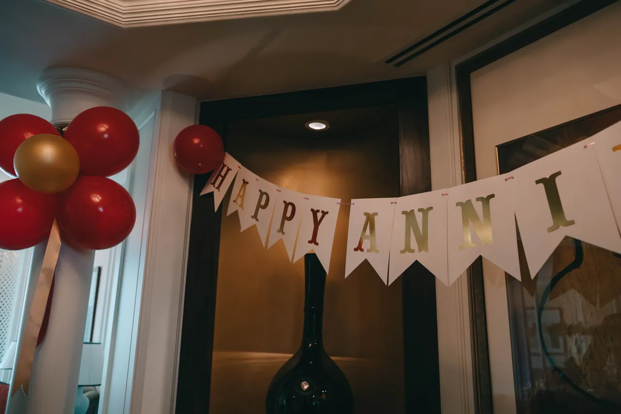 A happy anniversary banner with red and gold balloons.