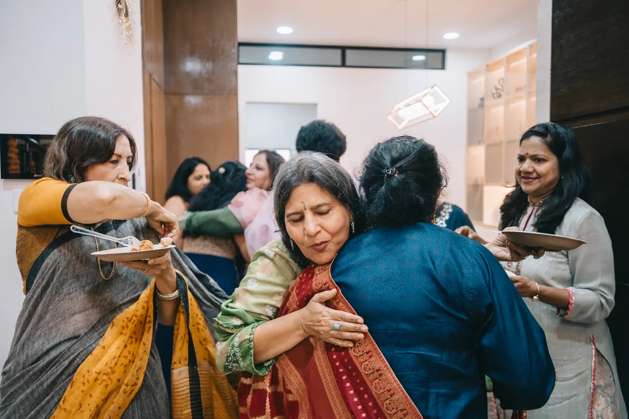 Two women hug as guests arrive.