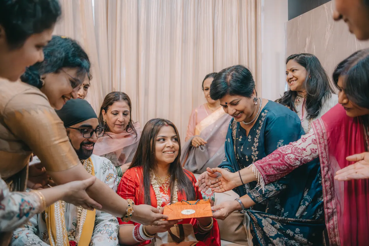 Women bless the bride as she sits on the sofa.