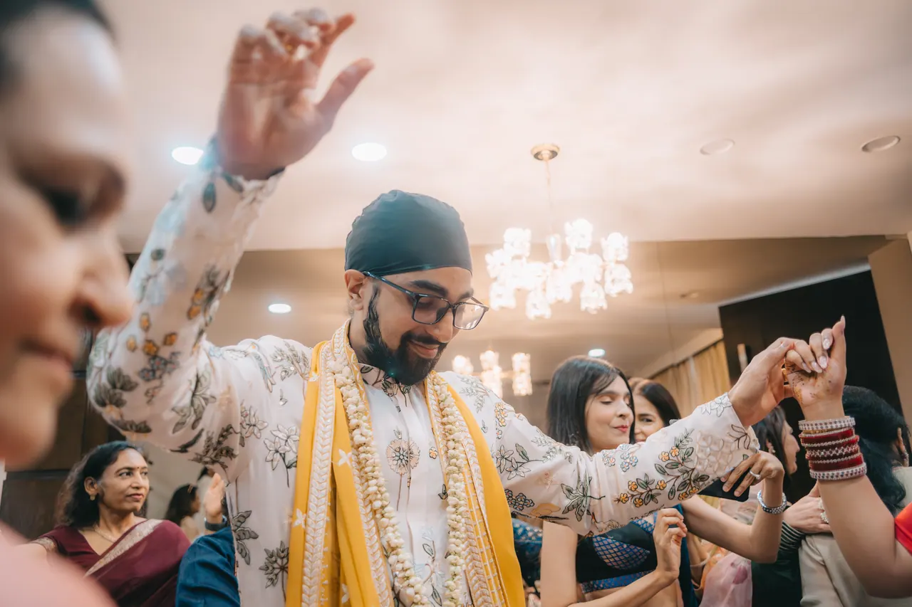 The groom dances with his arms raised.