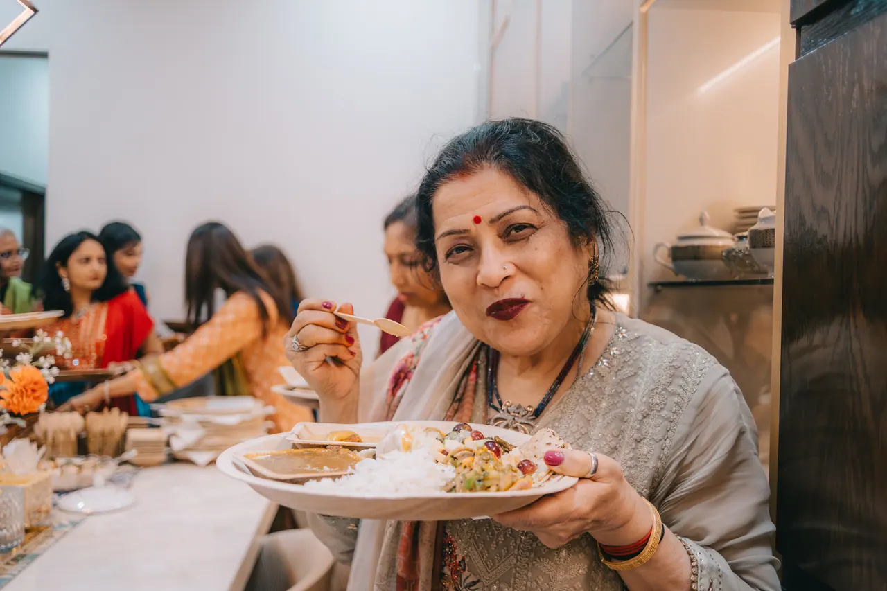 A woman smiles over a plate of food.